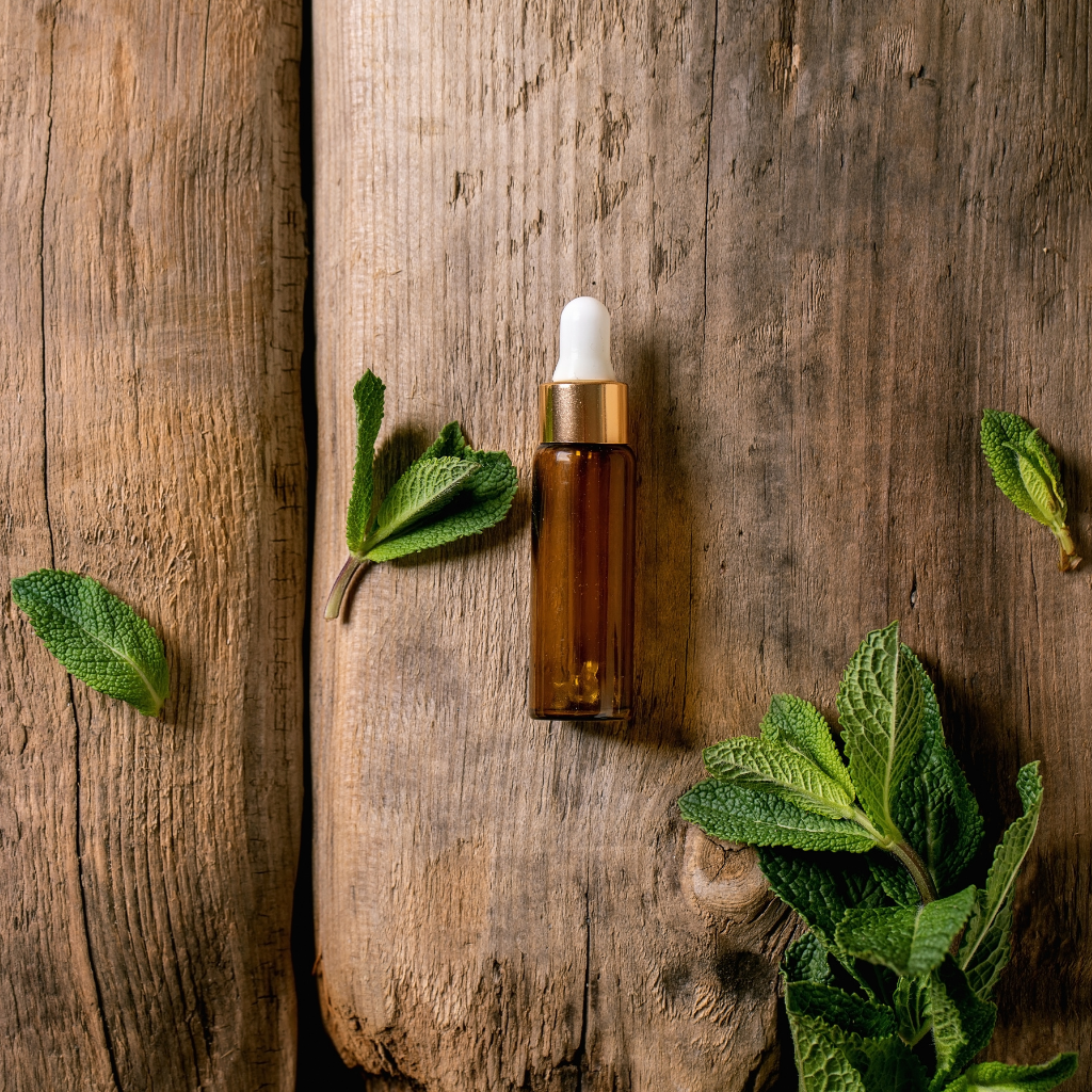 Brown glass dropper bottle with green leaves on a wooden surface