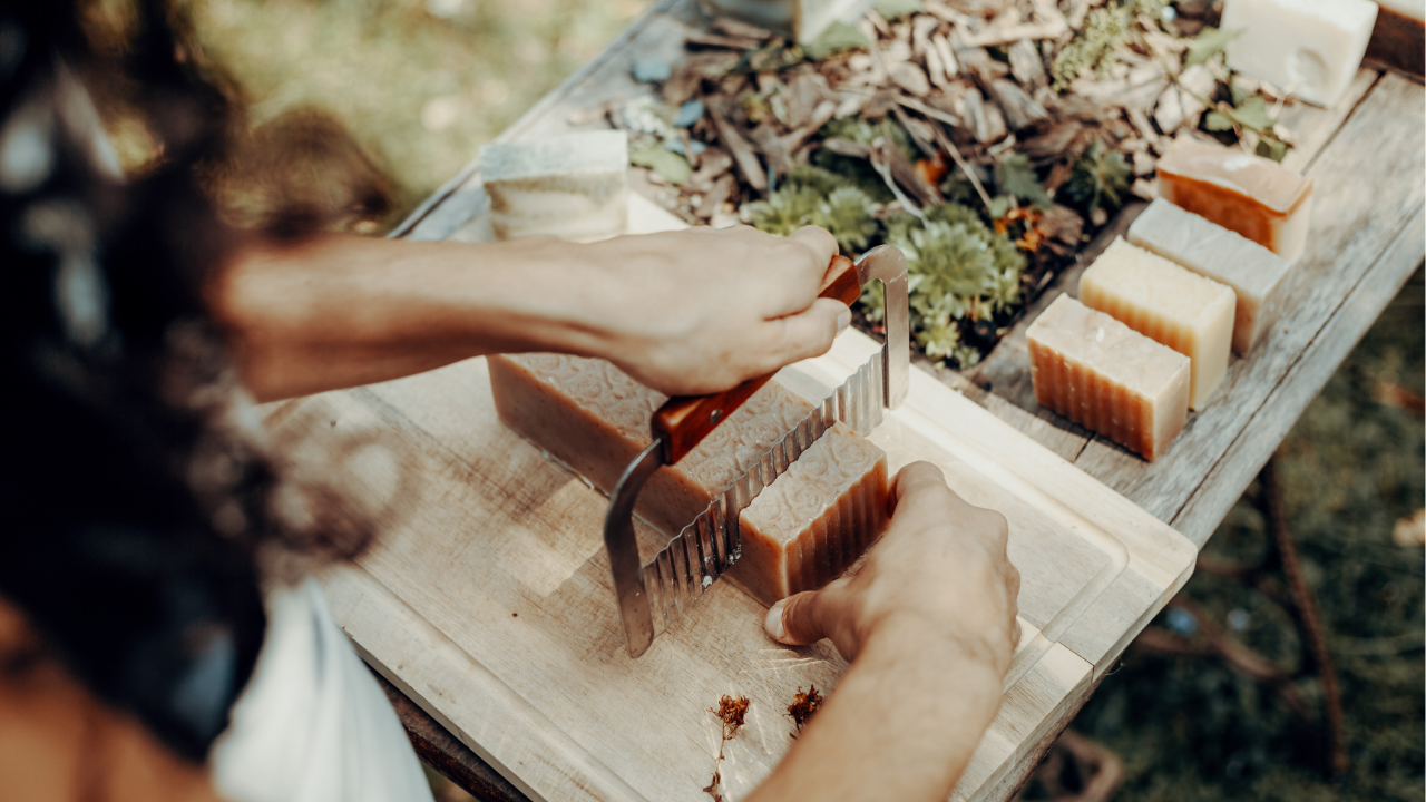 Person cutting soap bars using cold process soap in Dubai on a wooden board outdoors