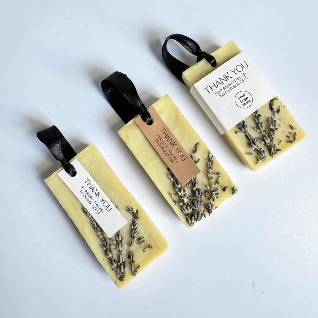 Three corporate gifts soap bars with lavender and black ribbons on a white background