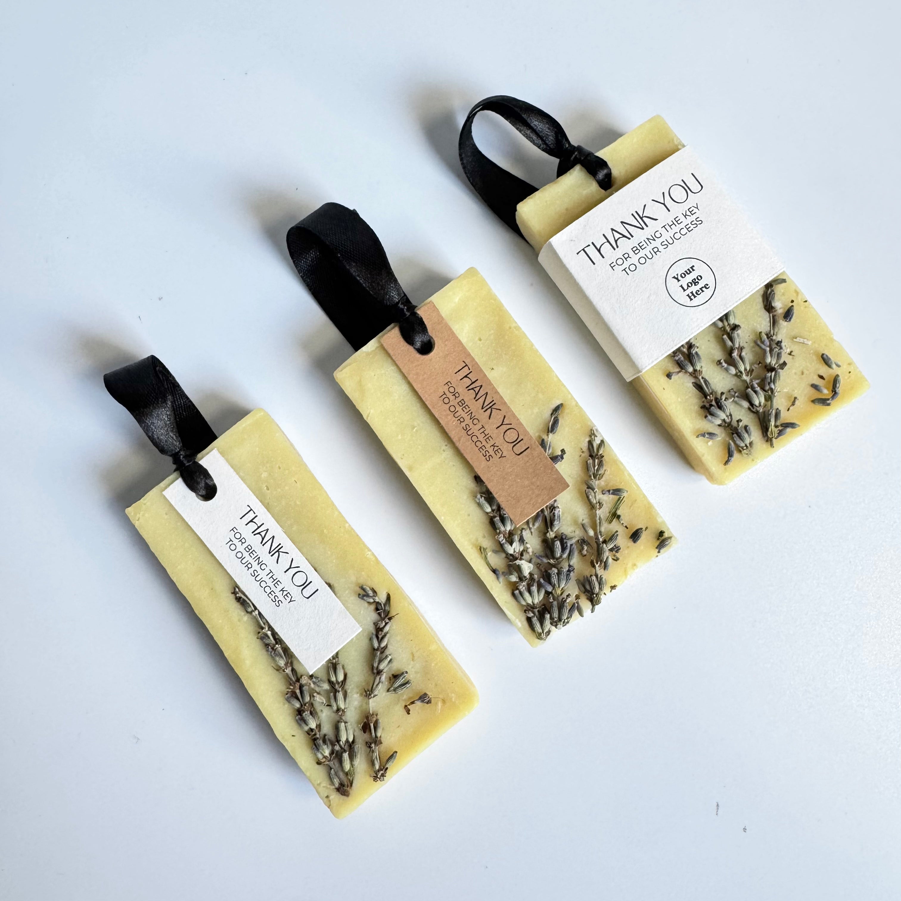 Three corporate gifts soap bars with lavender and black ribbons on a white background