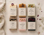 Collection of personalized soap bars with decorative packaging on a textured surface.