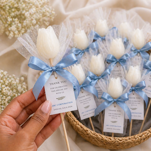 White tulip soap flowers on sticks with blue ribbons and 'Thank You' tags, held by a hand as a custom gift foe events and celebrations