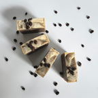 Four brown coffee natural soap bar with coffee beans above view in circle with dried jasmine flowers on a light gray background