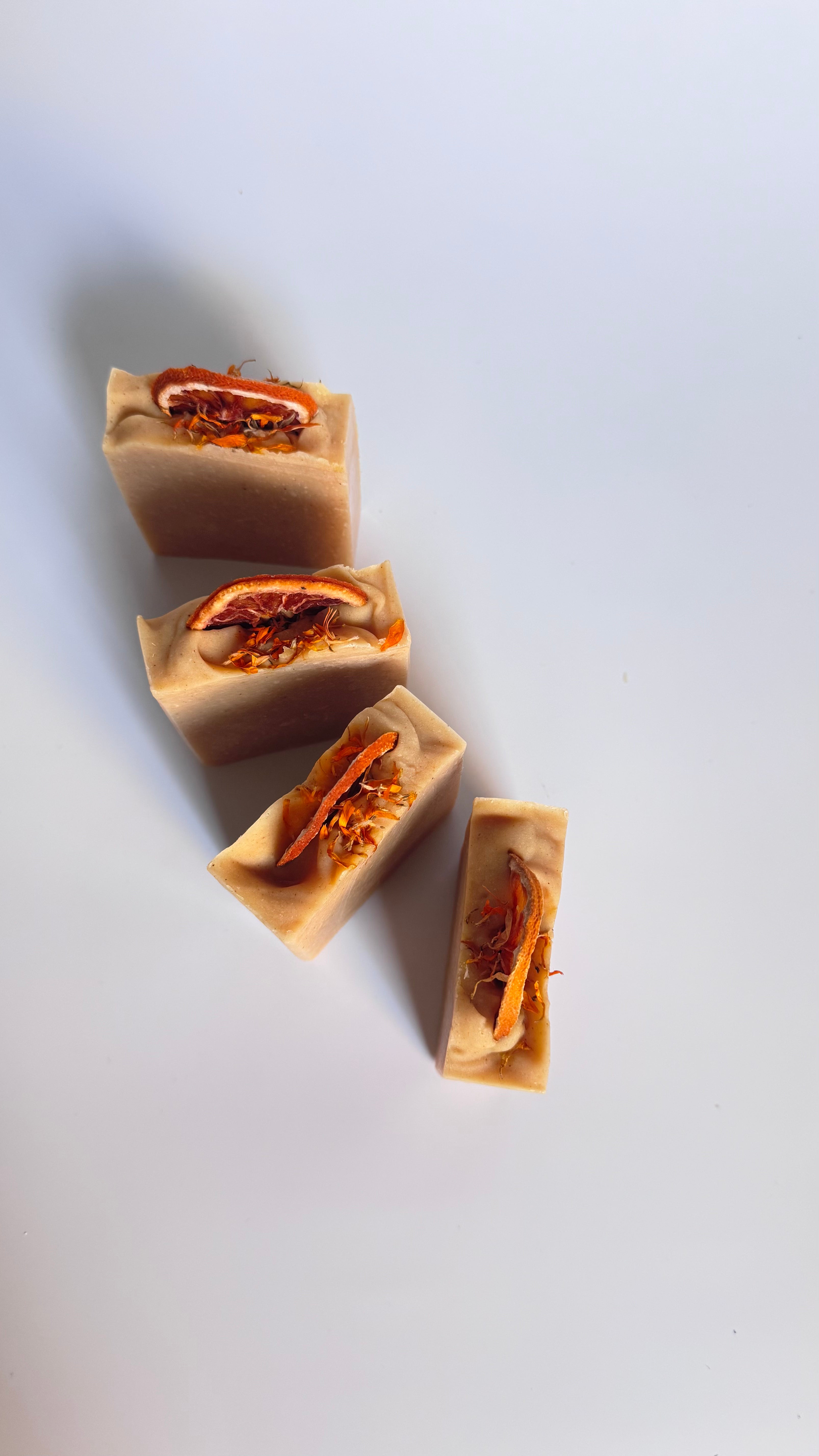 Four orange turmeric natural soap bar above view in circle with dried orange slices on a white background 