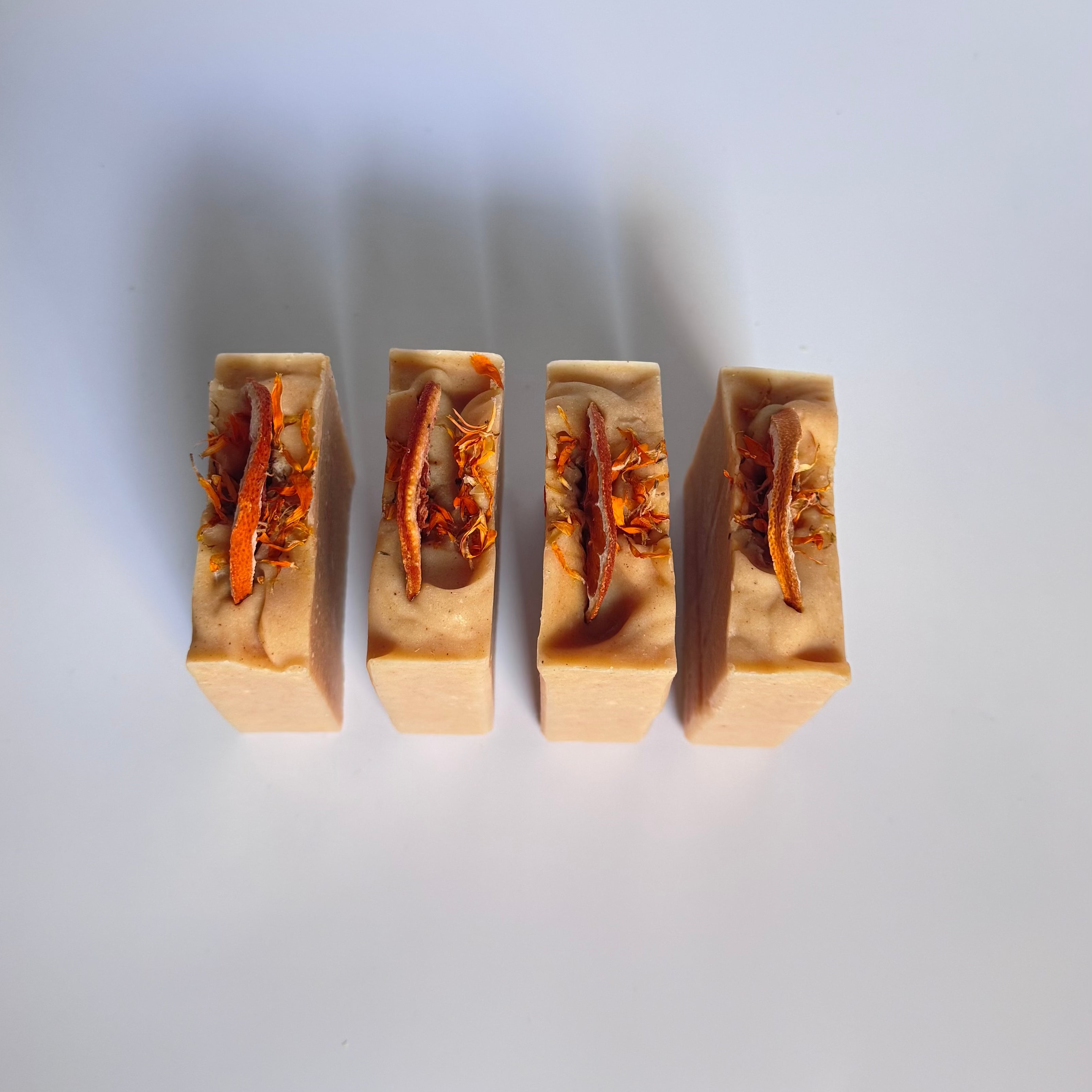 Four orange turmeric natural soap bar above view with dried orange slices on a white background 