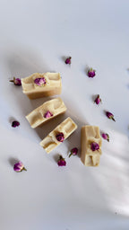 Four white beige cream coconut milk natural soap bars in circle with dried pink roses on a white surface 