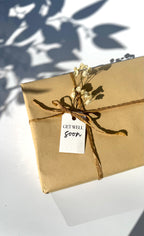 Gift wrapped in brown paper with a 'Get Well Soon' tag on a white surface.