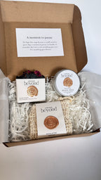 Gift set with black activated charcoal lavender tea tree soap bar, mini travel soaps and soap pouch and a packaging labeled 'La Boutique Beyond' inside a brown box on a white background 