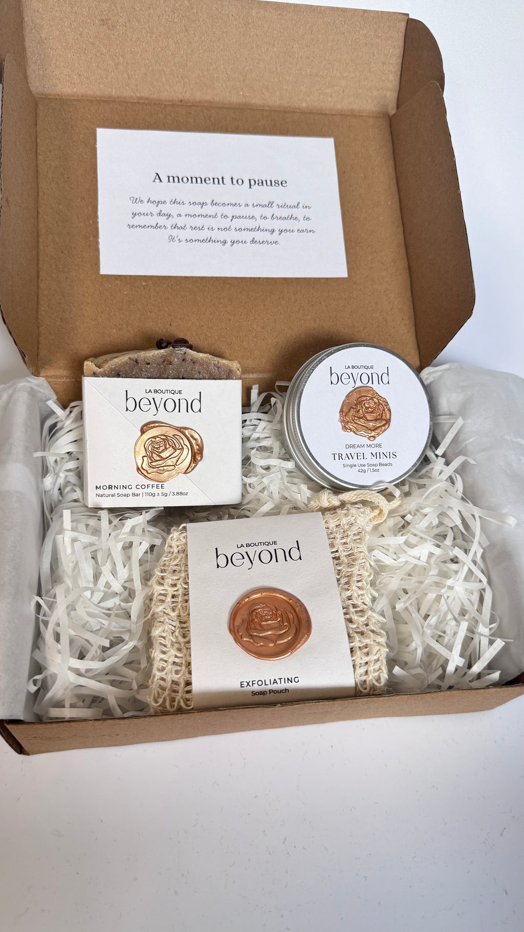 Gift set with brown coffee soap bar, mini travel soaps and soap pouch and a packaging labeled 'La Boutique Beyond' inside a brown box on a white background 