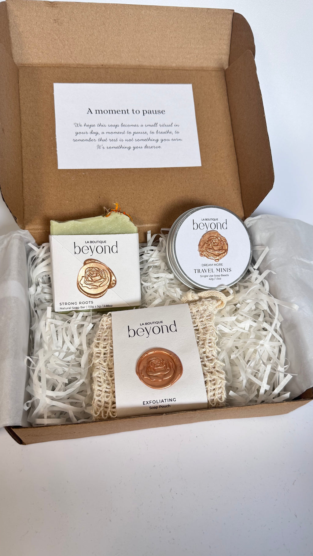 Gift set with green rosemary and cedarwood soap bar, mini travel soaps and soap pouch and a packaging labeled 'La Boutique Beyond' inside a brown box on a white background 