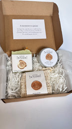 Gift set with green rosemary and cedarwood soap bar, mini travel soaps and soap pouch and a packaging labeled 'La Boutique Beyond' inside a brown box on a white background 