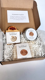 Gift set with orange turmeric soap bar, mini travel soaps and soap pouch and a packaging labeled 'La Boutique Beyond' inside a brown box on a white background 