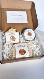 Gift set with white coconut soap bar, mini travel soaps and soap pouch and a packaging labeled 'La Boutique Beyond' inside a brown box on a white background 