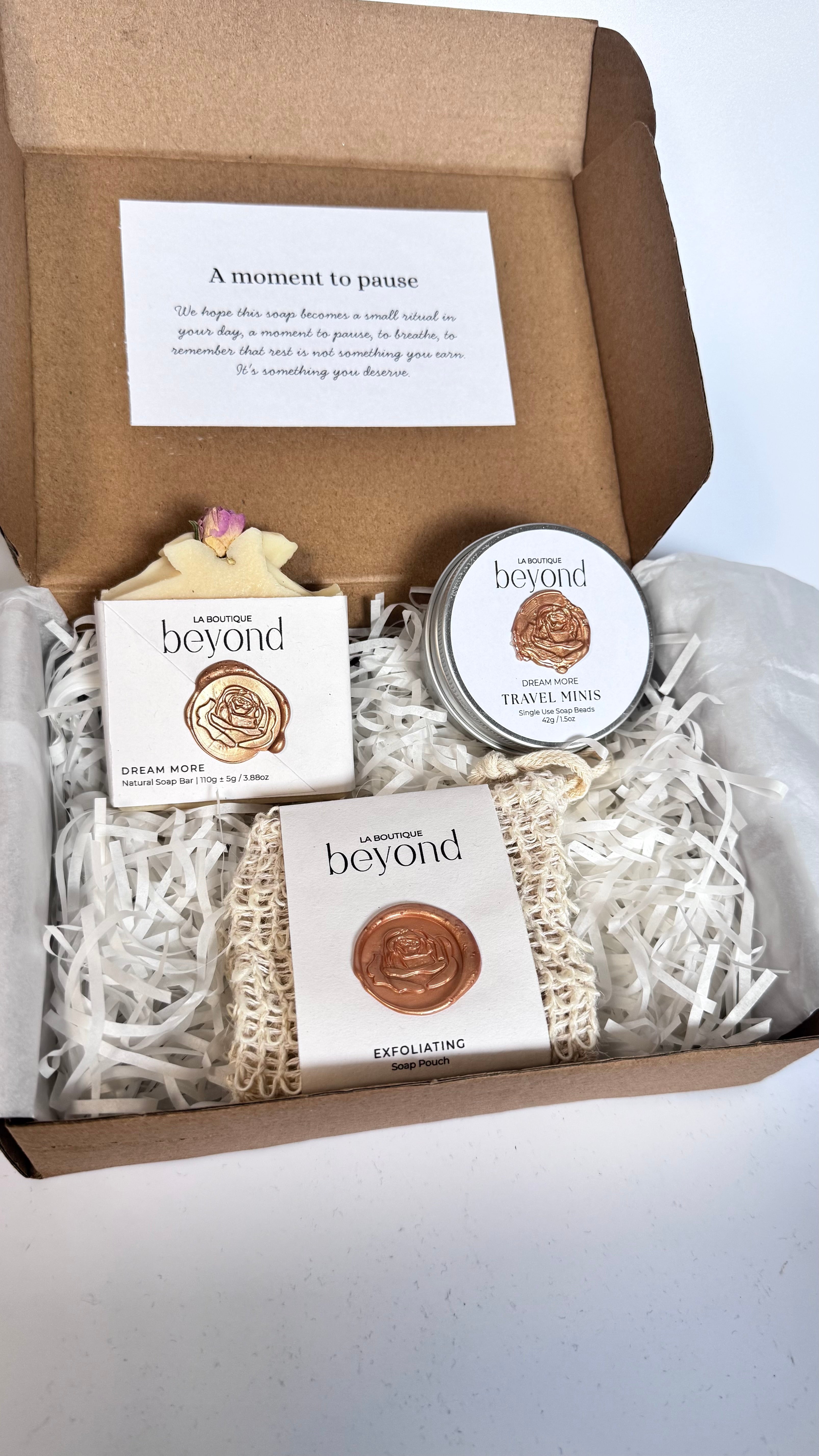 Gift set with white coconut soap bar, mini travel soaps and soap pouch and a packaging labeled 'La Boutique Beyond' inside a brown box on a white background 