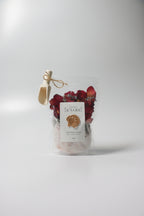 Bag of natural bath soak, Epsom salt Himalayan pink salt with dried red rose petals, lavender buds with 'La Boutique Beyond' label on a white background