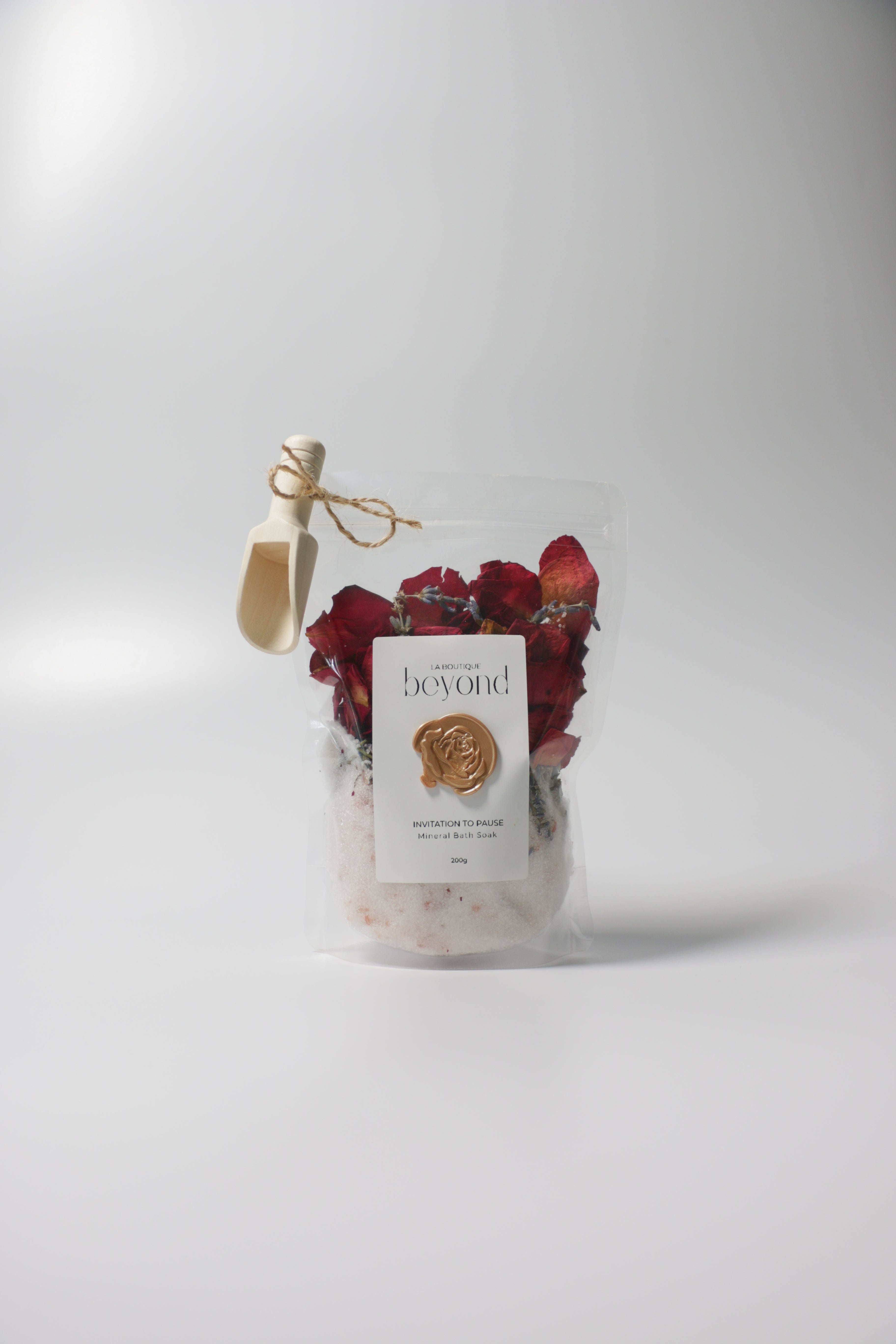 Bag of natural bath soak, Epsom salt Himalayan pink salt with dried red rose petals, lavender buds with 'La Boutique Beyond' label on a white background