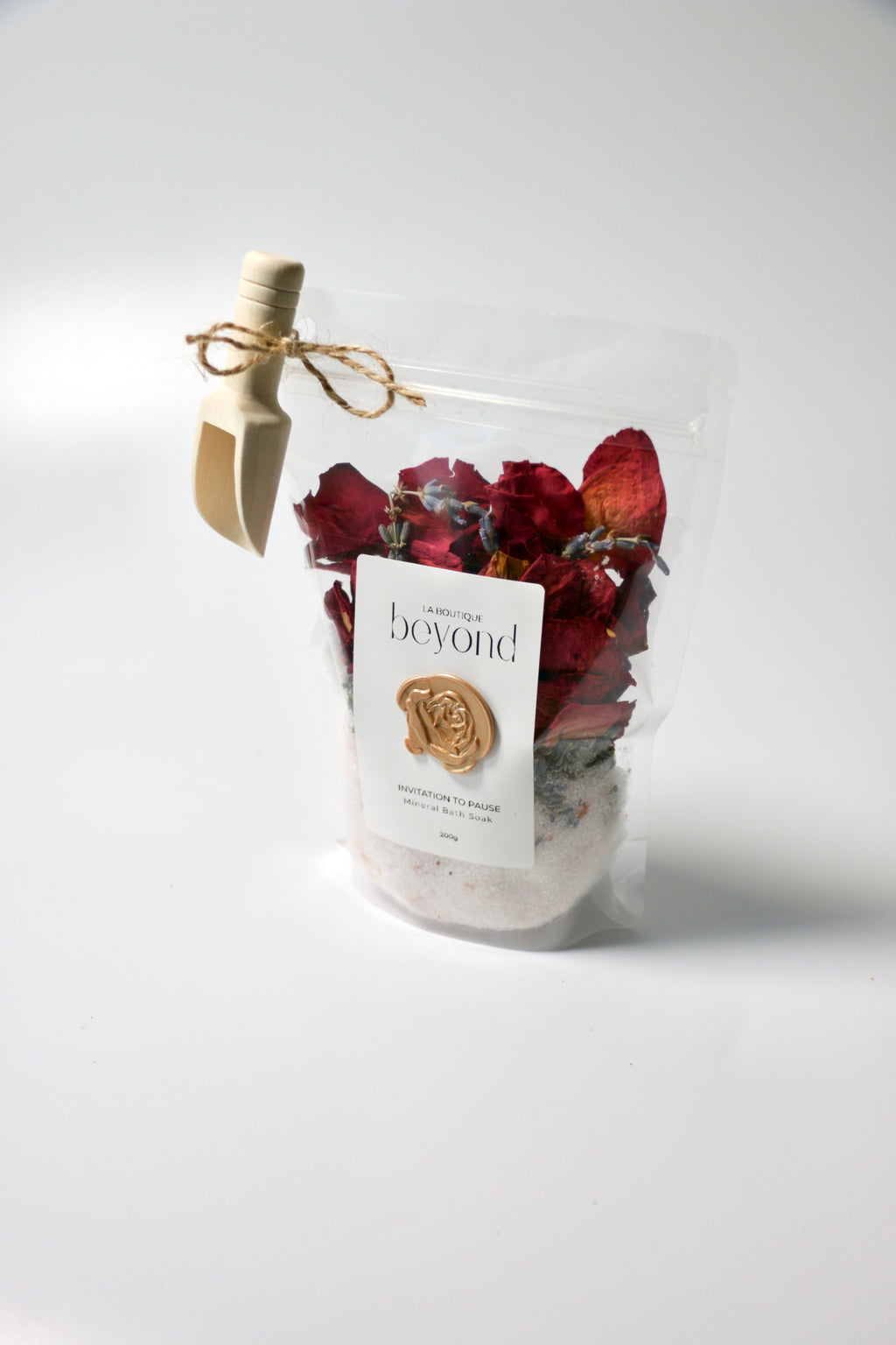 Bag of natural bath soak, Epsom salt Himalayan pink salt with dried red rose petals, lavender buds with 'La Boutique Beyond' label on a white background