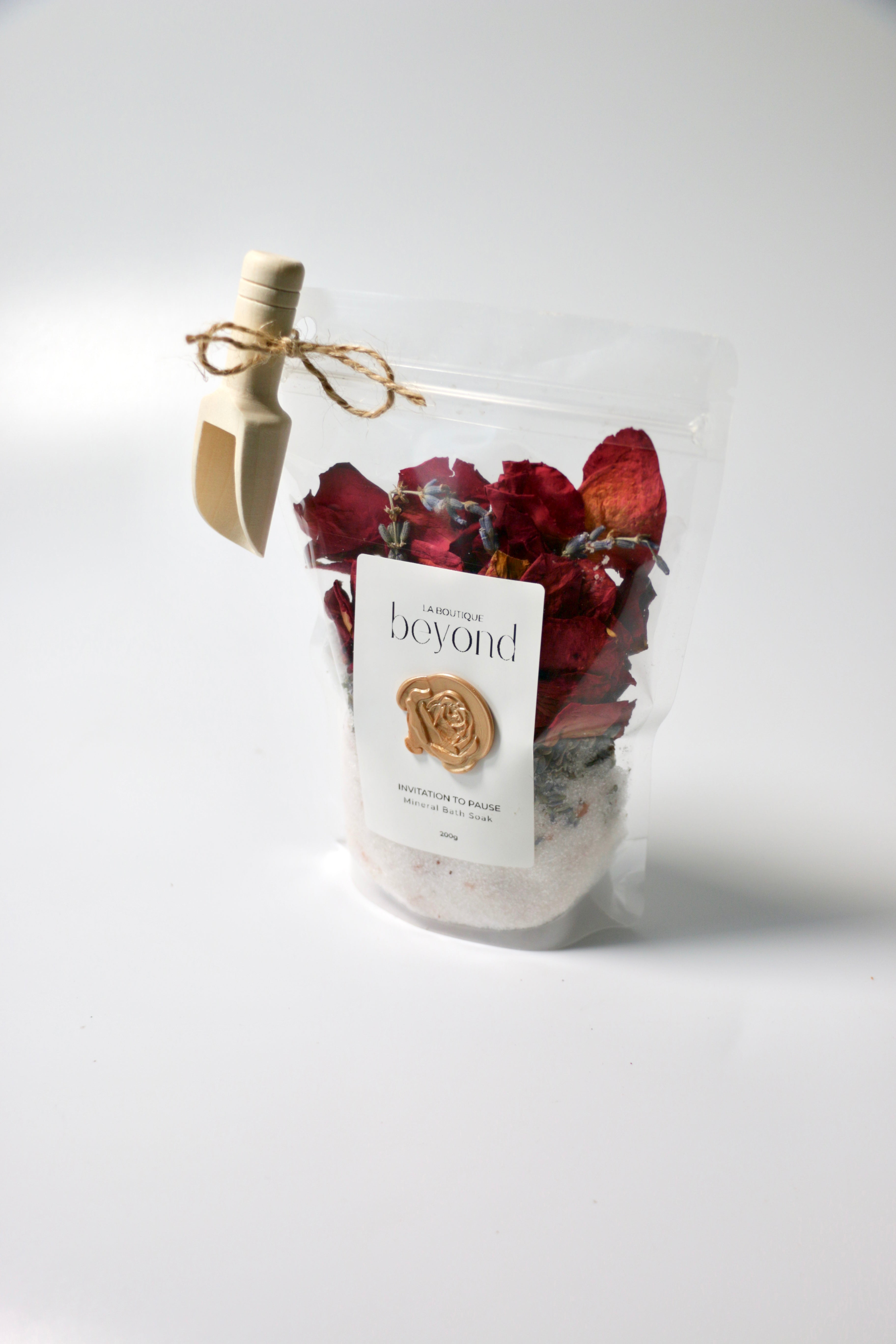Bag of natural bath soak, Epsom salt Himalayan pink salt with dried red rose petals, lavender buds with 'La Boutique Beyond' label on a white background