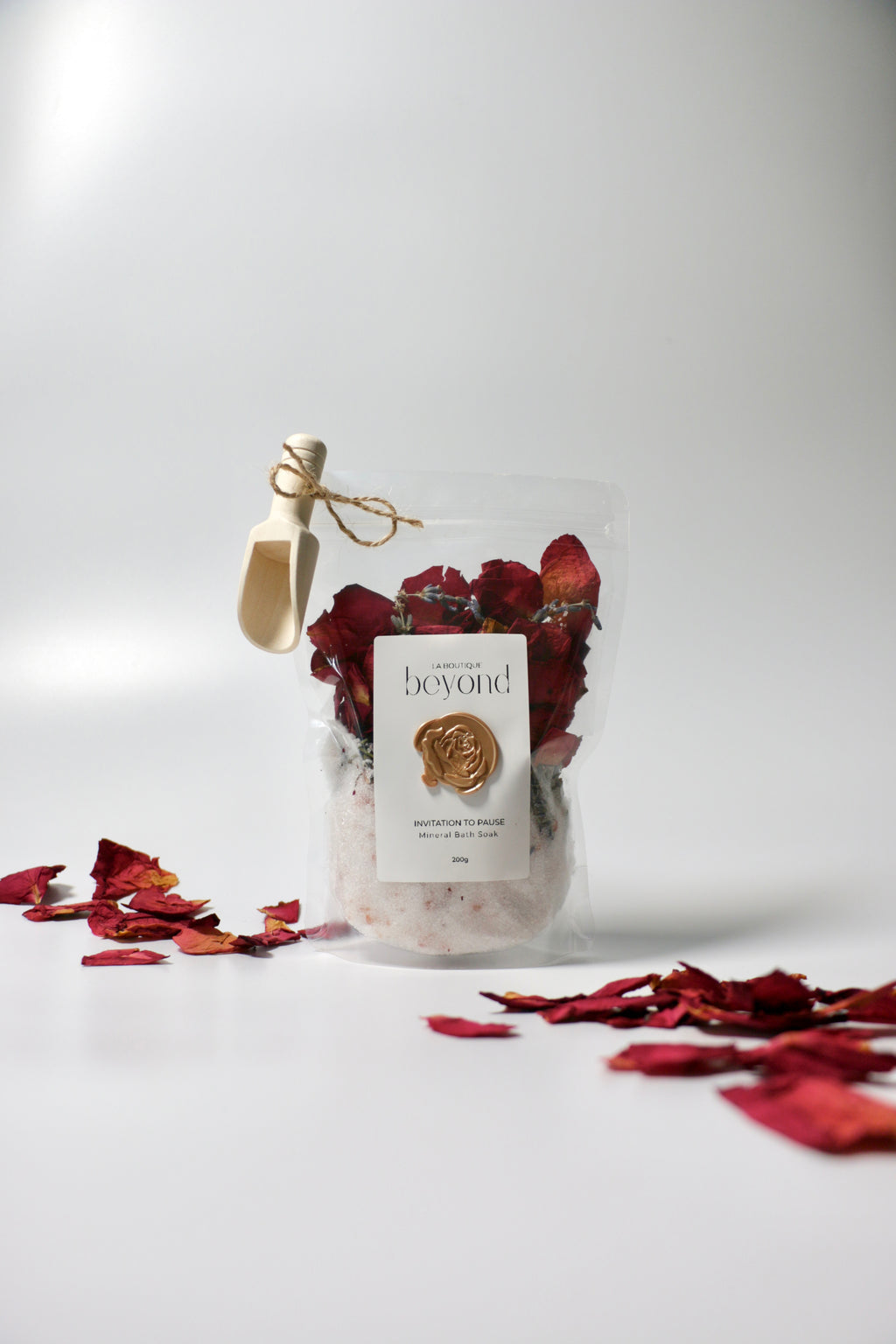 Bag of natural bath soak, Epsom salt Himalayan pink salt with dried red rose petals, lavender buds with 'La Boutique Beyond' label on a white background