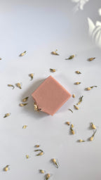 Pink chamomile rose geranium natural soap bar flat above view with dried jasmine flowers on a light gray background