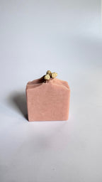 Pink chamomile rose geranium natural soap bar front view with dried jasmine flowers on a light gray background