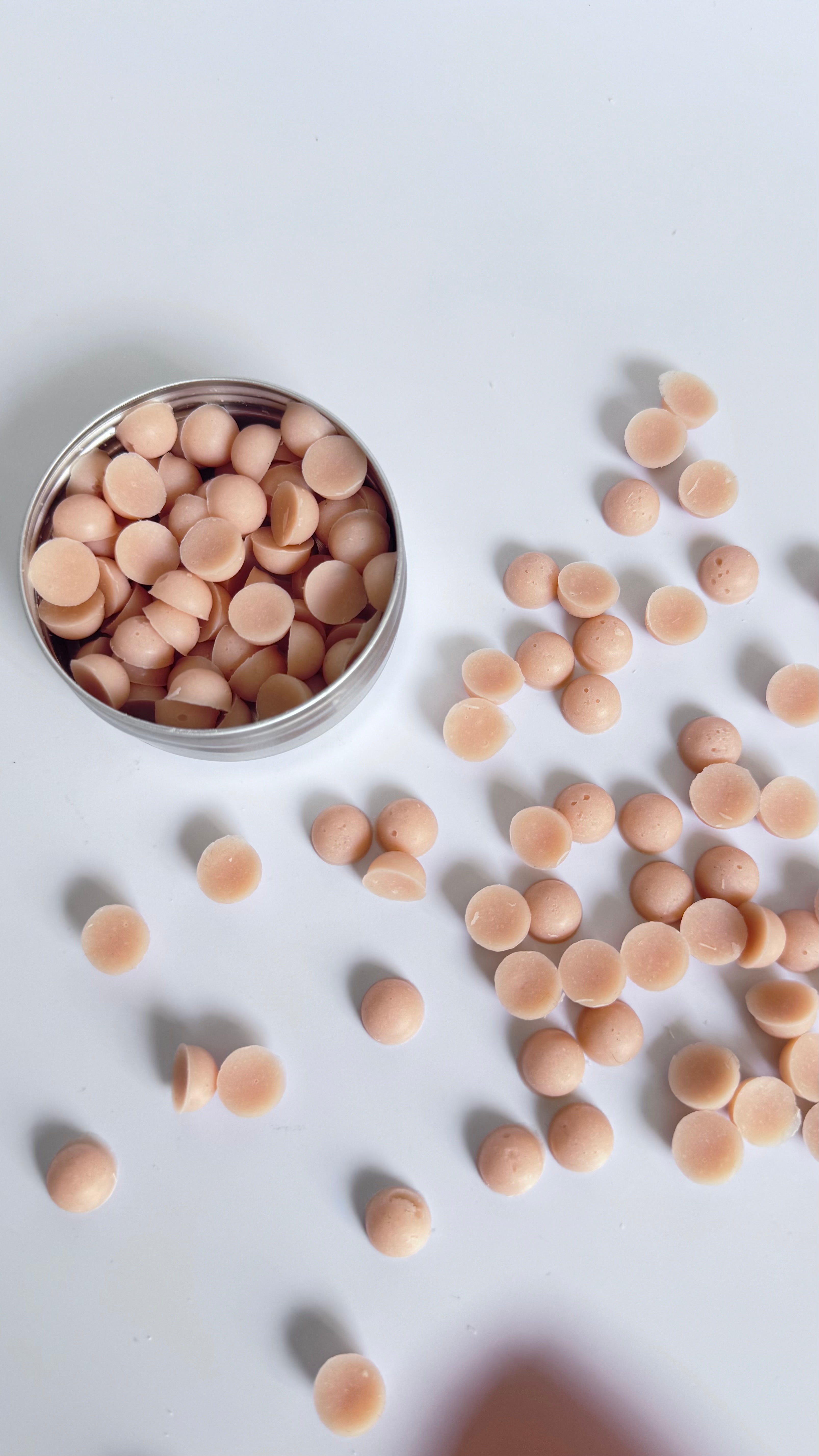 Pink rose geranium chamomile mini travel soap beads in a round tin box on light background