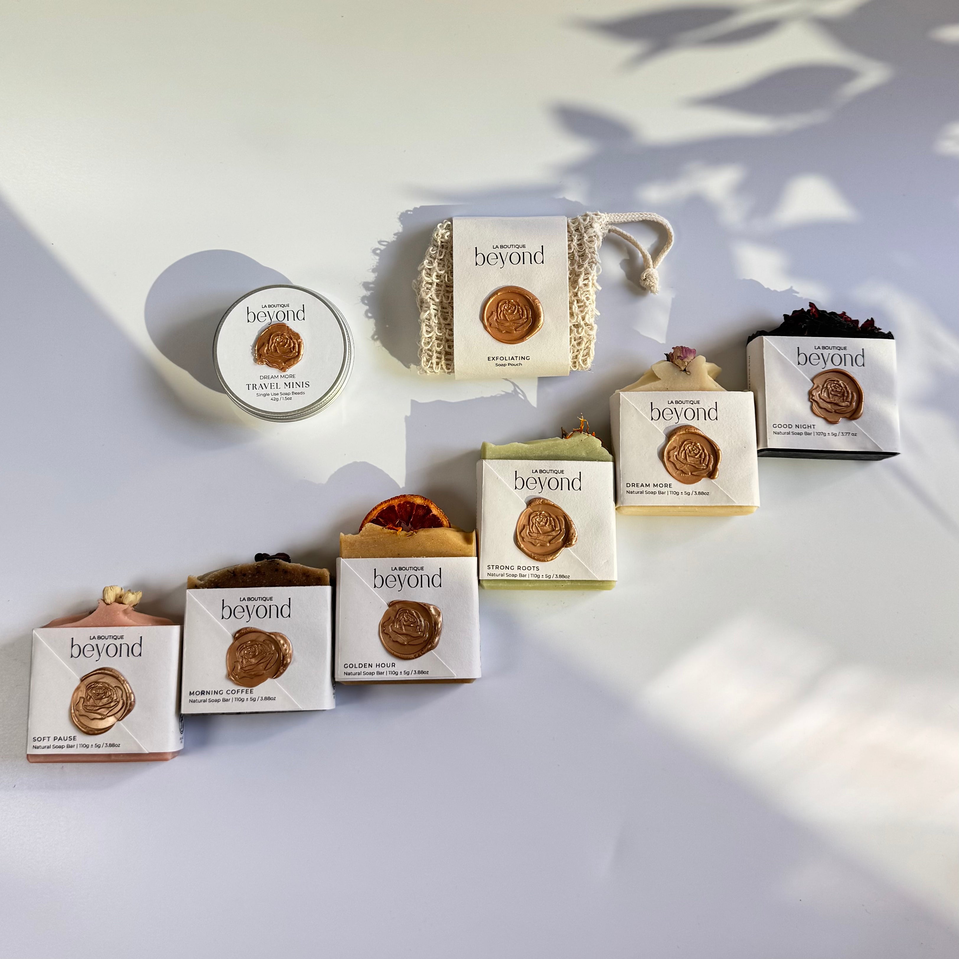 Row of soap bars  with soap pouch and mini travel soaps to choose from for the gift set box of 'La Boutique Beyond' coffee packages on a light gray background