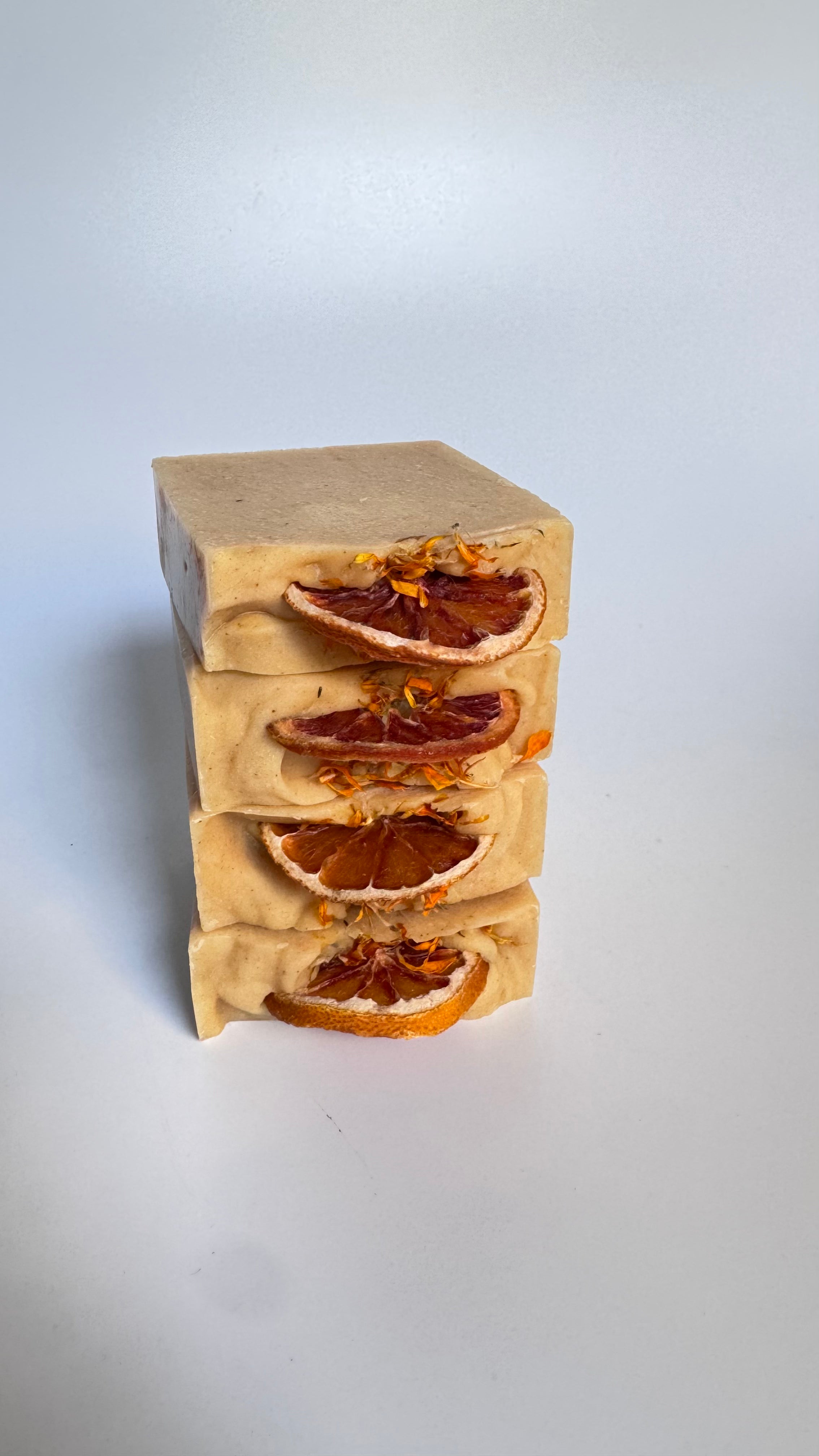 Stack of four orange turmeric natural soap bar with dried orange slices on a white background 