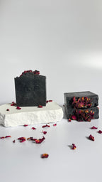 Stack of three black activated charcoal lavender tea tree natural soap bar with dried rose petals on a white background 