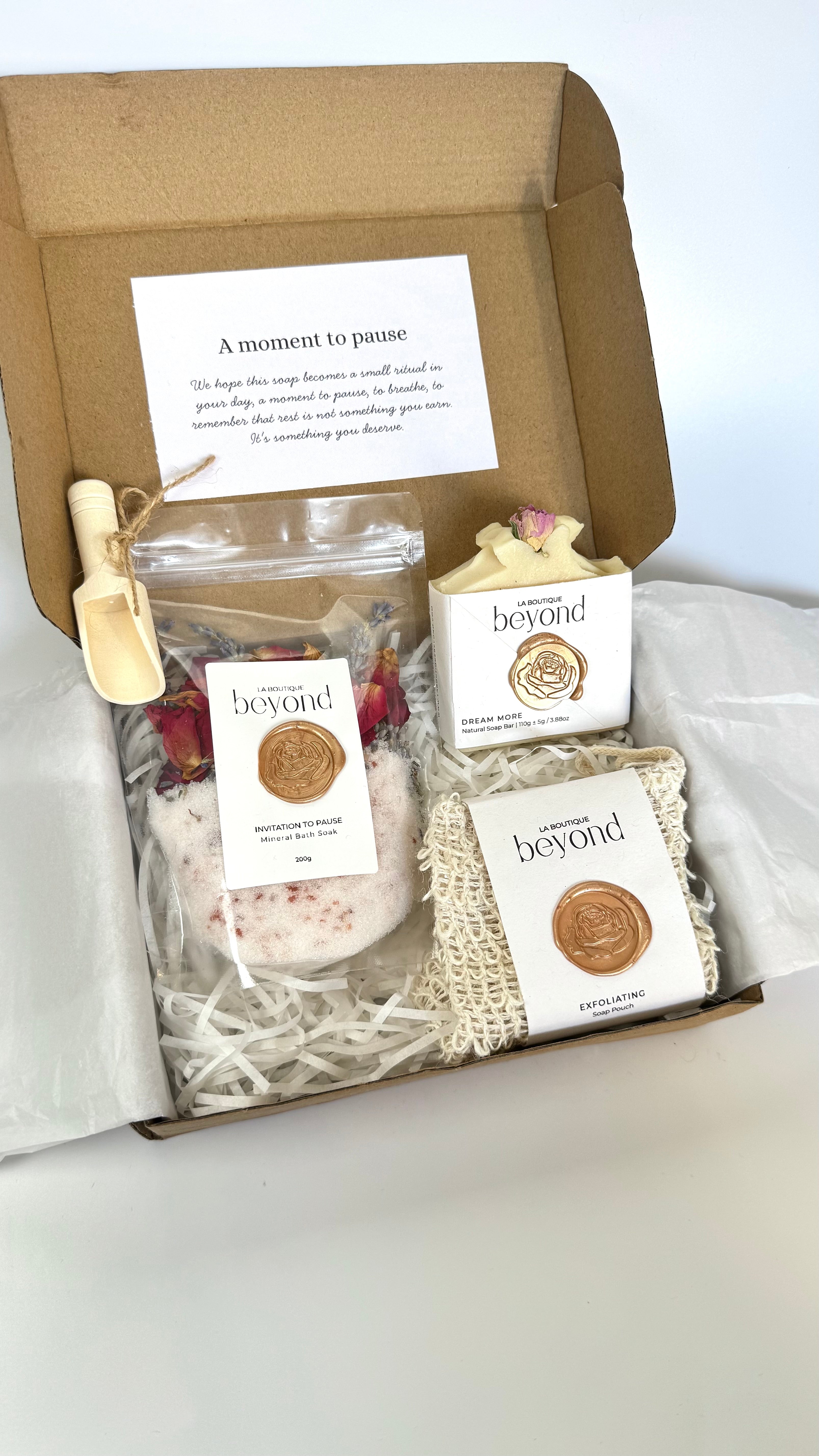 White coconut soap bar with soap pouch and bath soak to choose from for the gift set box of 'La Boutique Beyond' coffee packages on a light gray background 