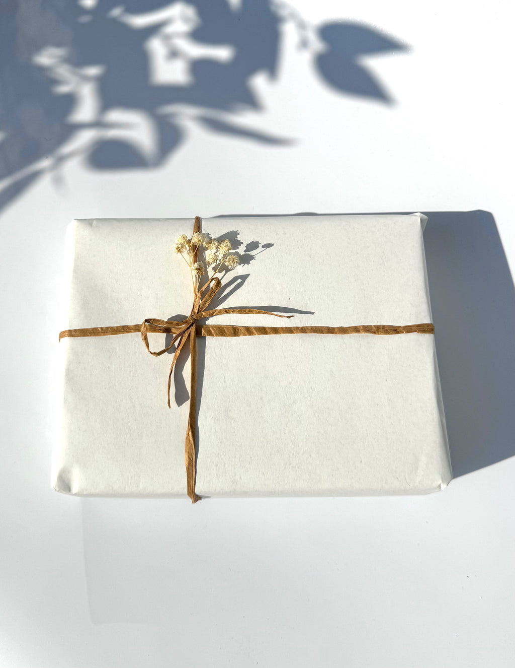 White gift box with gold ribbon and floral decoration on a white background