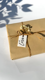 Gift box wrapped in brown paper with a 'With Love' tag on a white surface.