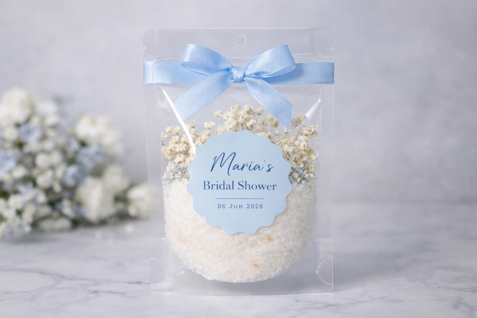 Bridal shower gift bag with bath soak and baby's breath and a blue ribbon on a light background