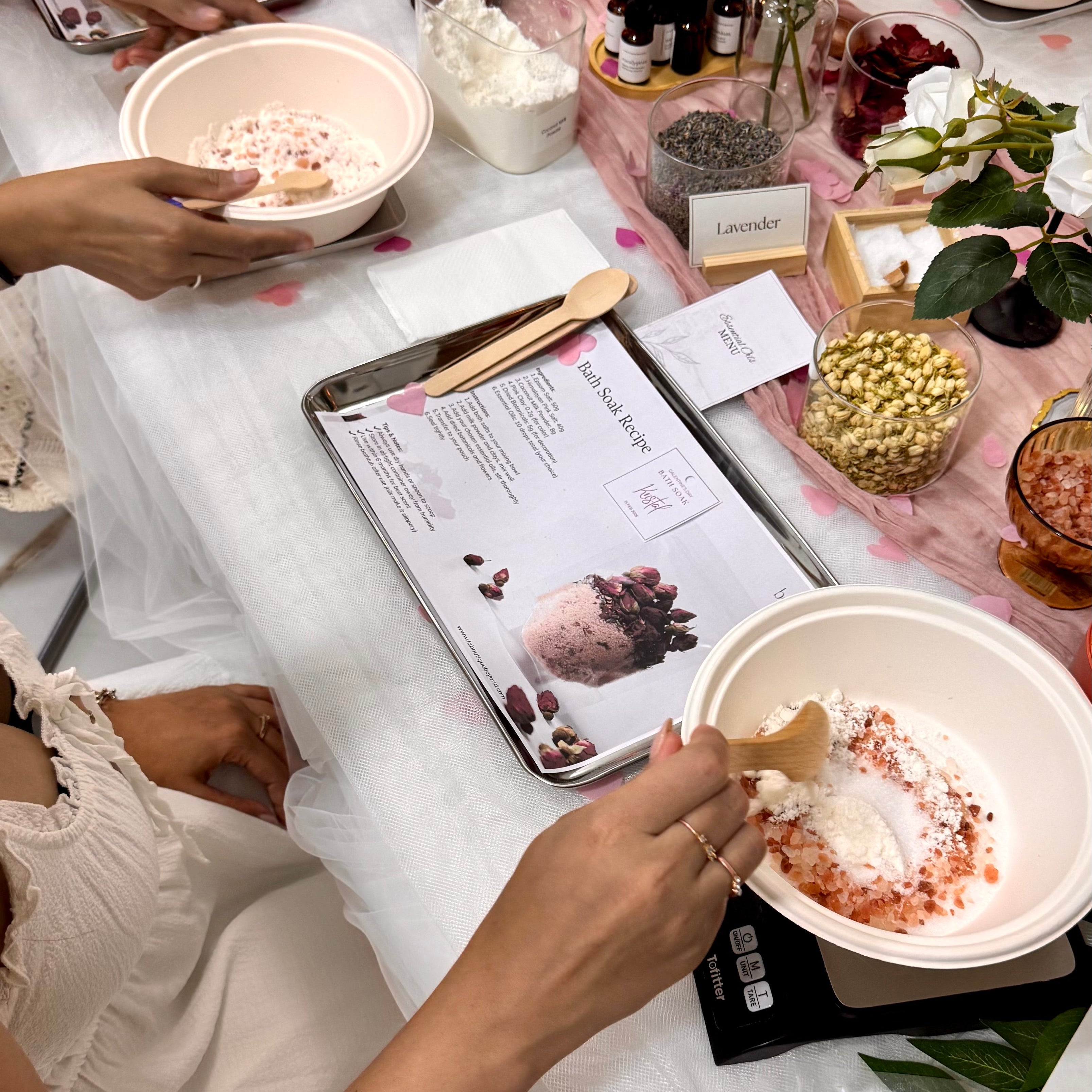 People making bath bombs at a table with ingredients and tools.