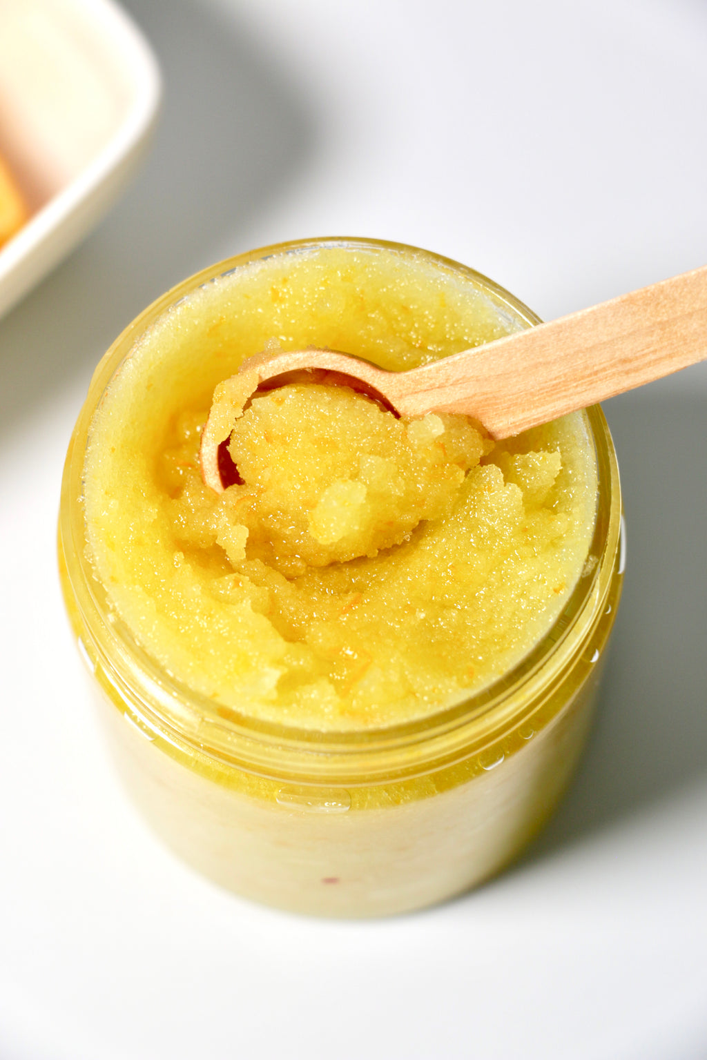 Close up Jar of orange zest sugar body scrub on a white background