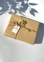 Gift box wrapped in brown paper with a 'Happy Birthday' tag on a white surface.