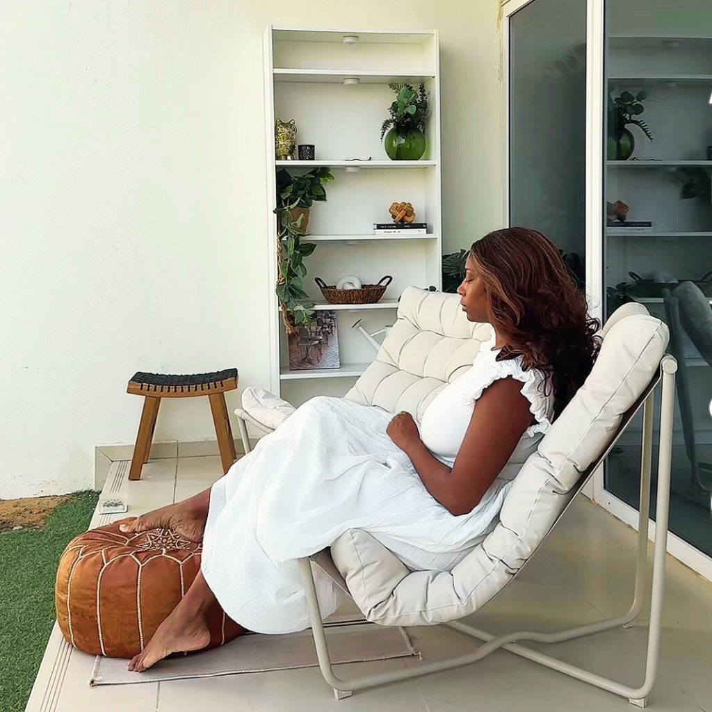 La Boutique Beyond founder  in a white dress sitting on a modern chair in a terrace 