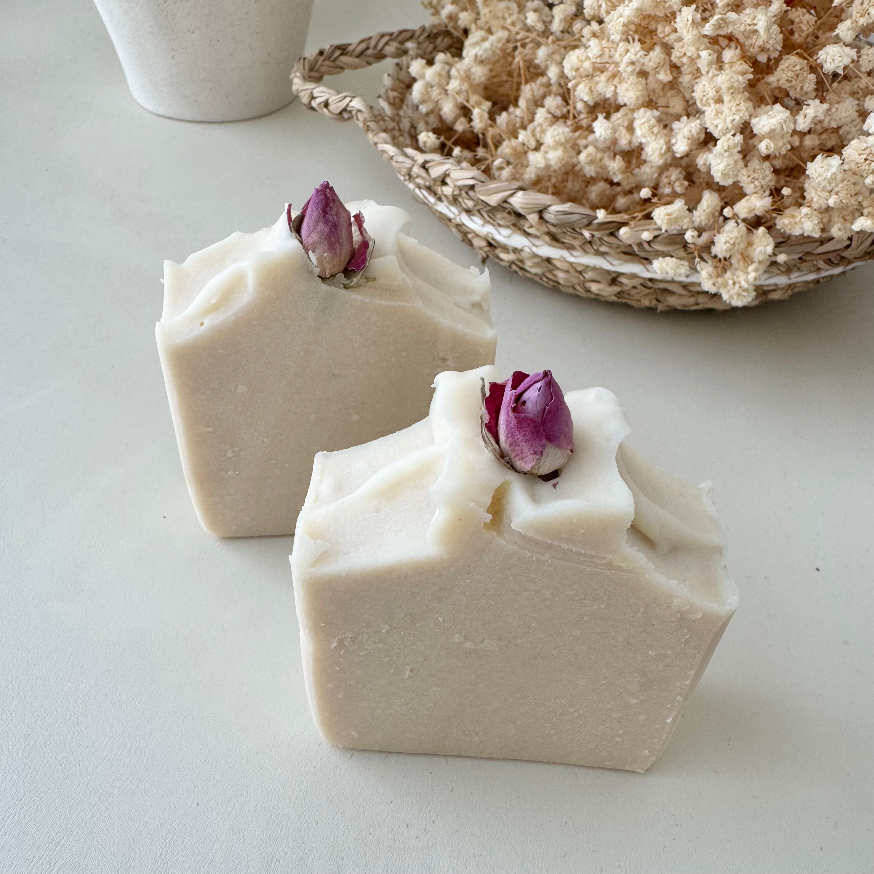 Stacked natural handmade coconut soap bars topped with dried rose buds