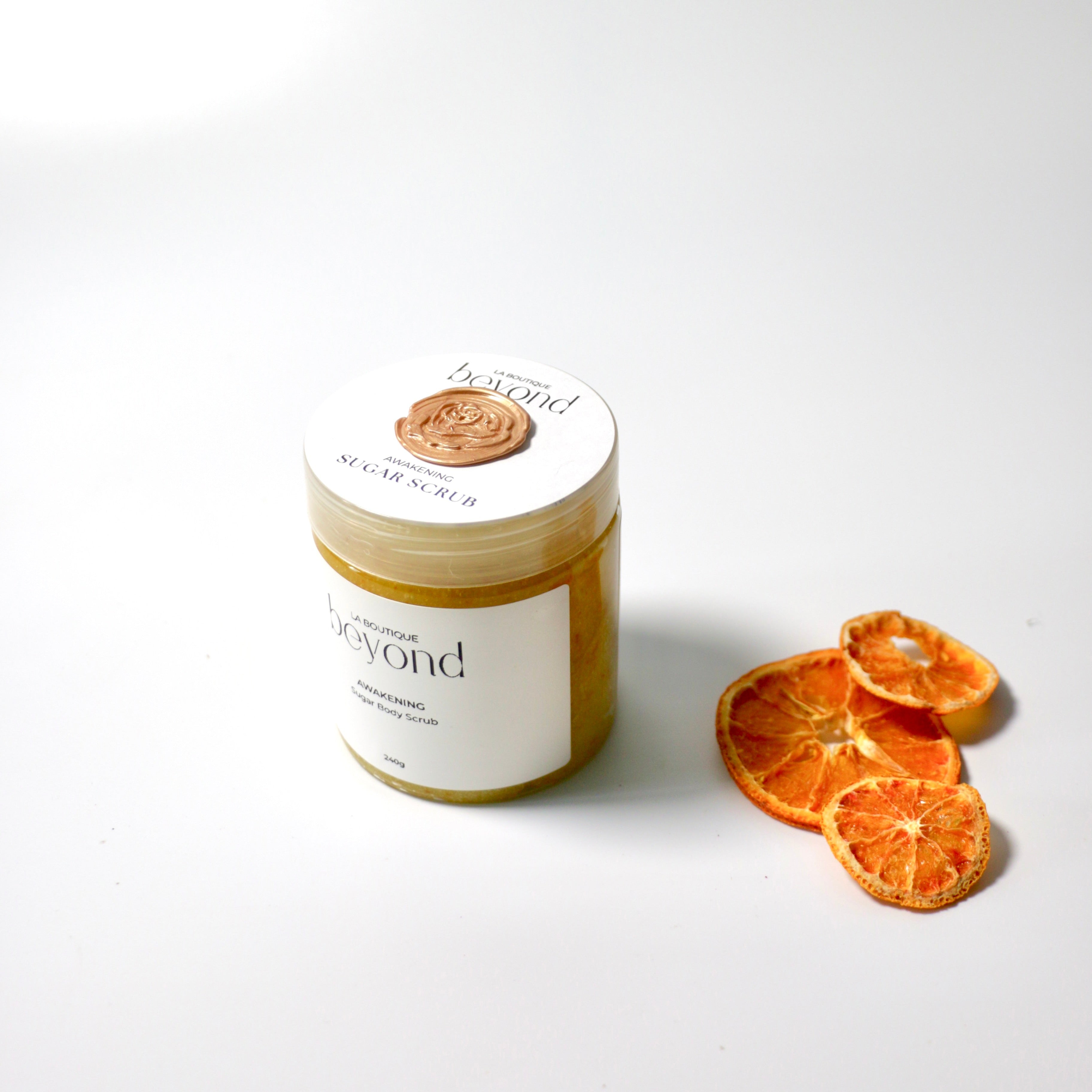 Jar of orange zest body sugar scrub with dried oranges on a white background