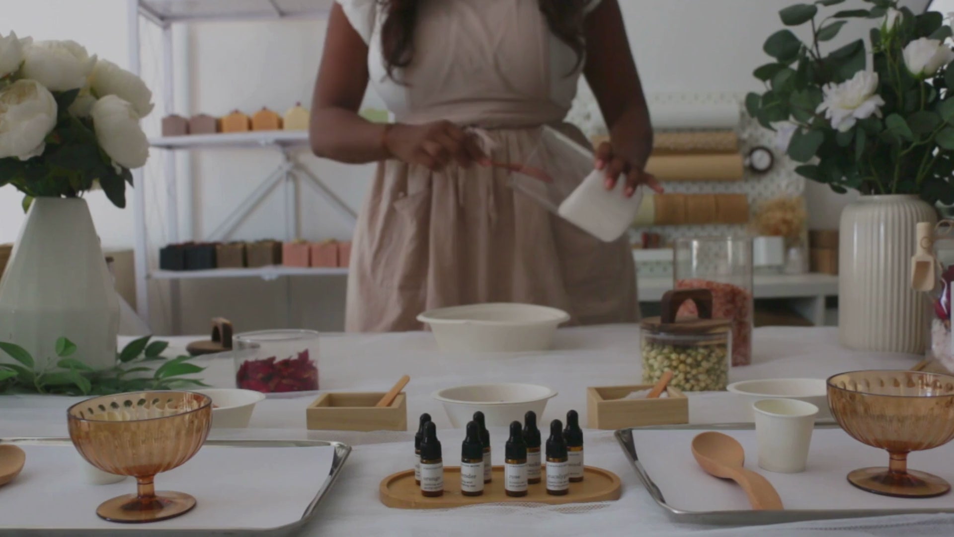 Table setup for live bath soak station in Dubai with various bowls, natural ingredients, and essential oils, and utensils on a white surface.
