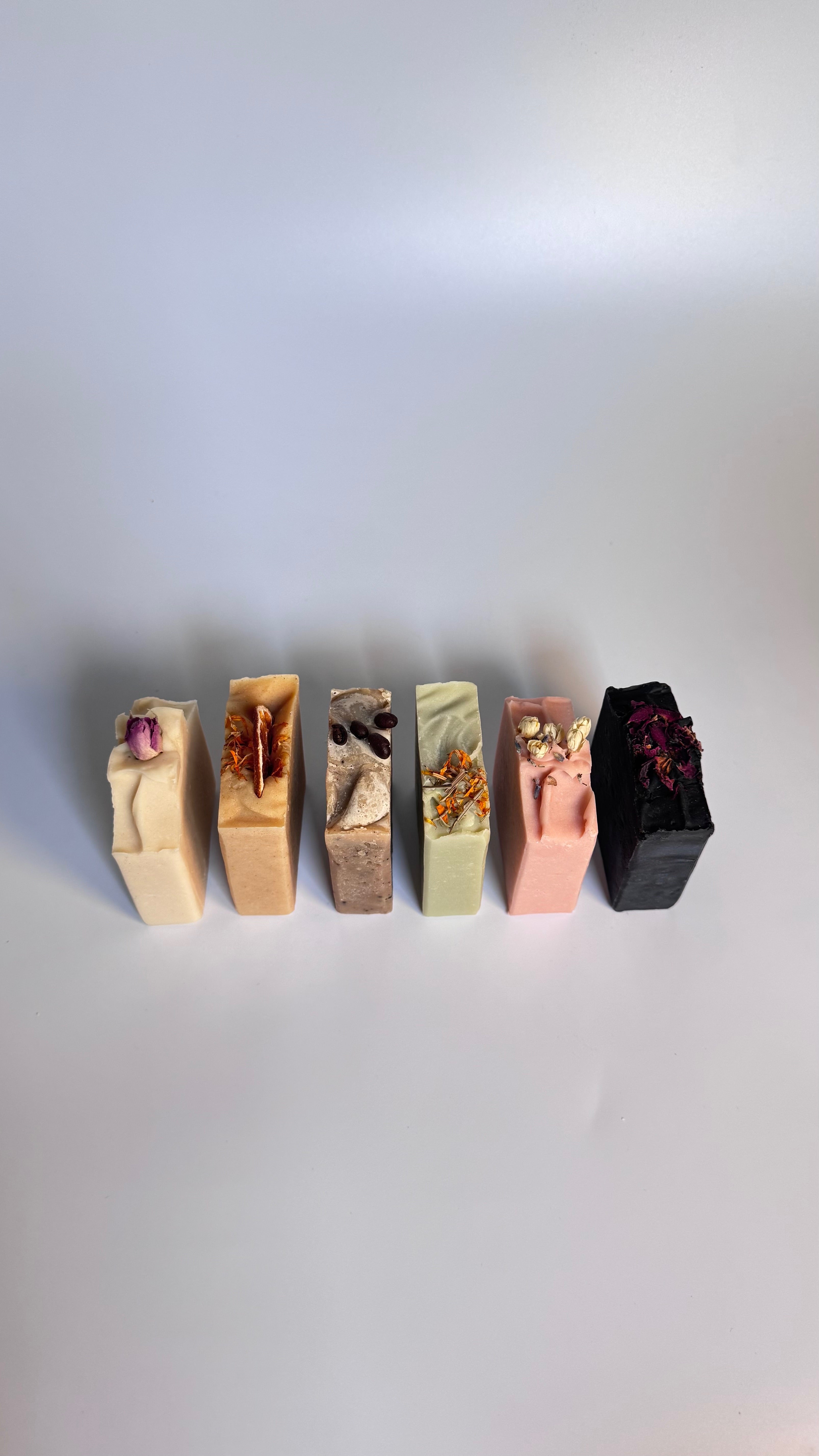 Set of six colorful soap bars with embedded flowers on a white background